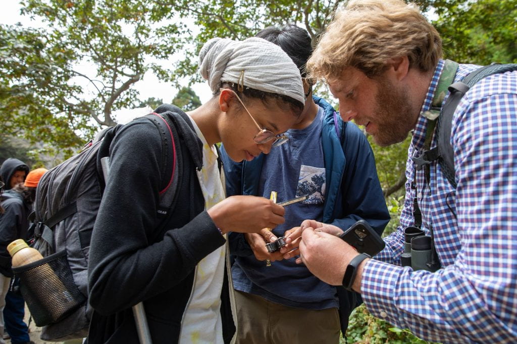 Faculty and students in the field examining a specimen.