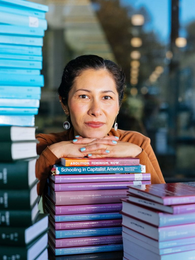 Grad student portrait with stacks of books.
