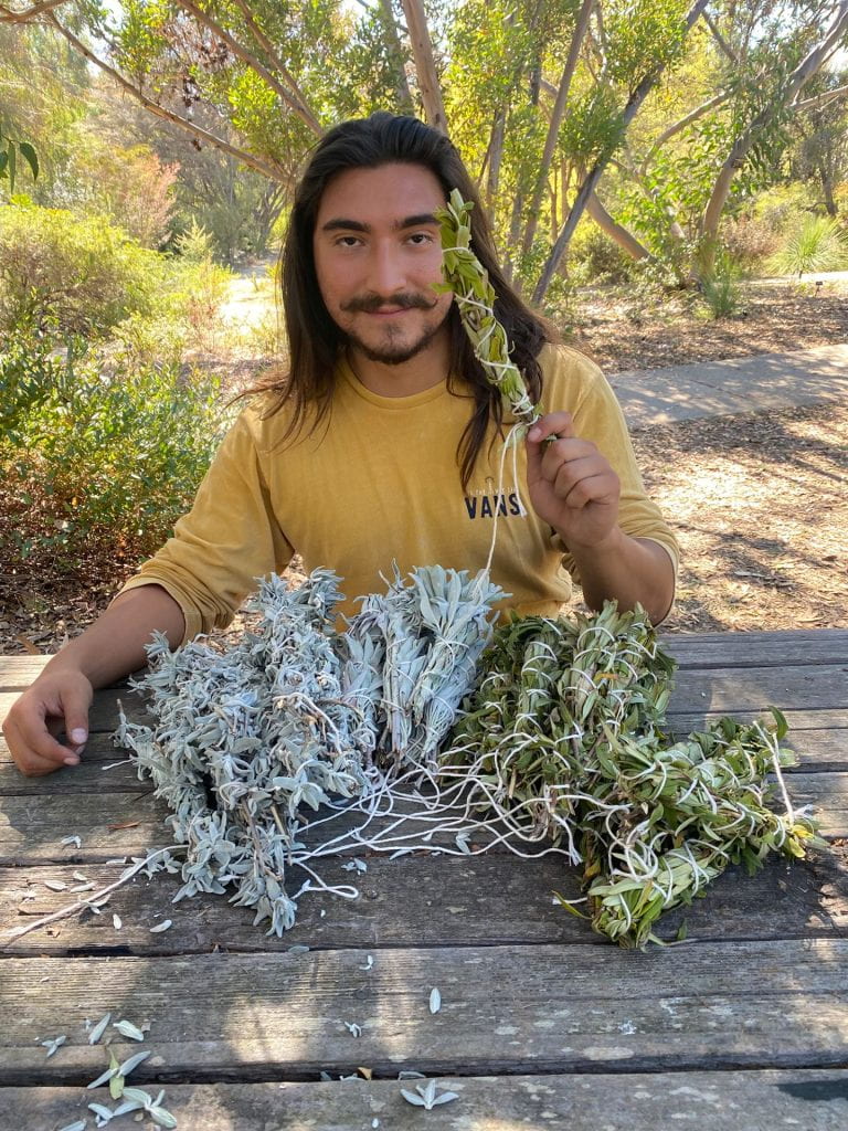 Indigenous person hold up some herbs.